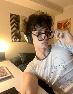 a young man wearing headphones sitting at a table in front of a laptop computer