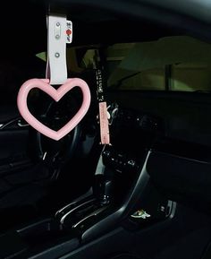 a car dashboard with a pink heart hanging from it's center console