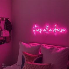 a pink neon sign that says it's all a dream on the wall above a bed