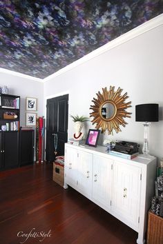 a living room with a ceiling that has flowers painted on the ceiling and wooden floors