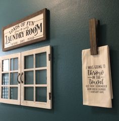 two signs hanging on the side of a green wall next to window panes and a sign that says laundry room