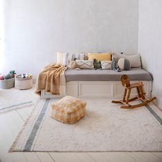 a room with a bed, rocking chair and rugs on the floor in front of it