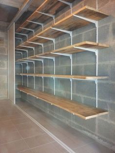 an empty room with several shelves on the wall and tile flooring in front of it