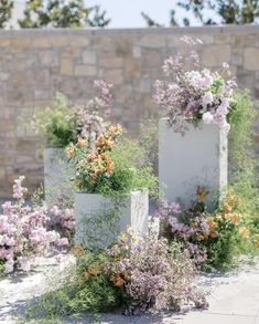 three white planters with flowers in them