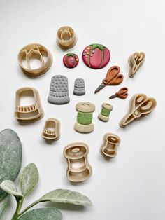 several different types of crafting supplies on a white surface next to a green plant