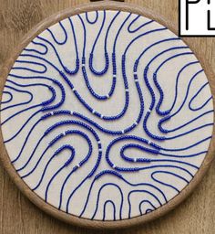 a blue and white embroidery pattern on a wooden hoop