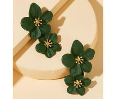 two green flower earrings sitting on top of a white surface