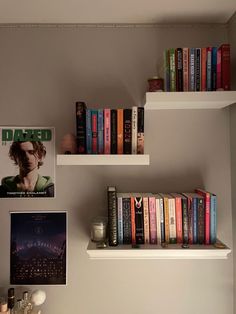 some books are sitting on white shelves in a room with gray walls and pictures above them