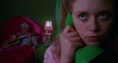 a woman is sitting in her bed talking on the phone and holding a green pillow