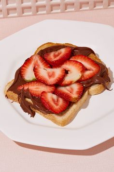 a piece of toast with chocolate and strawberries on it sitting on a white plate