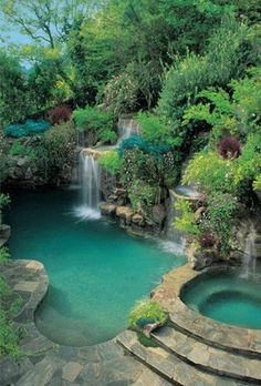 an outdoor swimming pool with steps leading up to it and waterfall in the back ground