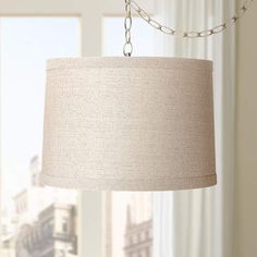 a lamp hanging from a chain in front of a window