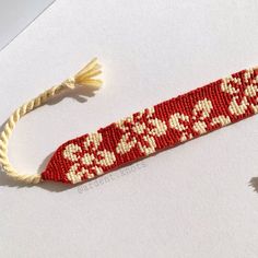 a red and white beaded bracelet with tassels on the end is shown