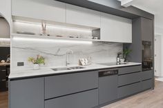 a modern kitchen with marble counter tops and gray cabinetry, along with hardwood flooring