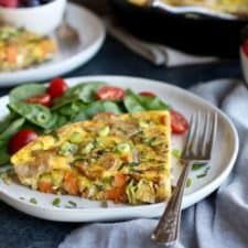 an omelet is on a plate with some fruit and salad in the background