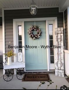 a blue front door with a wreath on it and a welcome mat in front of it