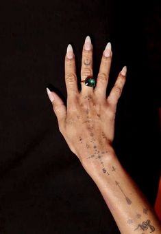 a woman's hand with tattoos and a ring on it