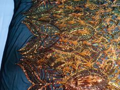 a blue and gold dress with sequins on the bottom is laying on a bed