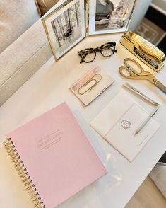 a table topped with pictures and notebooks on top of a white table next to a chair