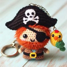 a crocheted keychain with a pirate hat and eye patch holding a parrot