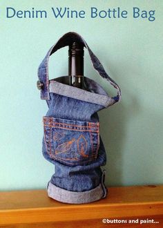 a wine bottle in a denim bag sitting on top of a wooden table next to a blue wall