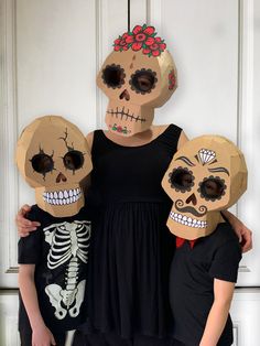 three people in costumes with masks on their heads and one wearing a skull mask, standing next to each other