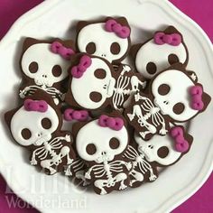 decorated cookies in the shape of skulls and panda bears on a white plate with pink ribbon