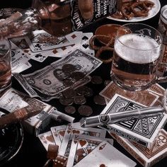 a table topped with lots of different types of playing cards and beer glasses on top of each other