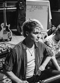 two young men sitting on the floor in front of guitars