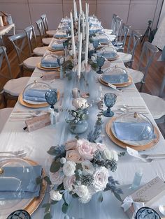 the table is set with blue and white plates, silverware, and floral centerpieces