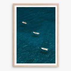 two small boats floating in the ocean with blue water and one white boat is seen from above