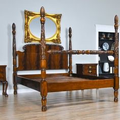 a wooden bed sitting on top of a hard wood floor next to a dresser and mirror