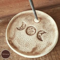 a ceramic plate with three phases of the moon on it and a spoon sticking out of one