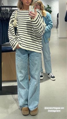 a woman taking a selfie with her cell phone in front of some clothing racks