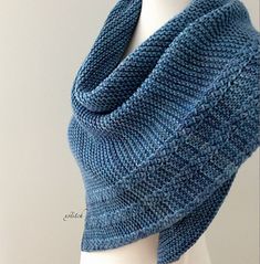 a blue knitted shawl draped over a white mannequin's head