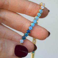 -14kt gold plated over brass -lab created blue opal ombre colors -6. 5'' length   A truly unique tennis bracelet made up of an ombre of blue opals and prong set. The bracelet measures 6. 5'' in length and can not be adjusted in length. To extend the life of your gold plated and vermeil jewelry, avoid wearing when washing hands, showering, applying lotion, using harsh cleaning supplies or working out. To clean, buff gently with a soft and dry 100% cotton cloth or a microfiber cloth. Do not use jewelry cleaner on gold plated jewelry. Tennis Jewelry, September Birthstone Jewelry, Solid Gold Earrings, Zodiac Jewelry, Vermeil Jewelry, Gifts For New Mums, Jewelry Ring Box, Pearl Jewellery Earrings, Men's Jewelry Rings