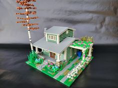 a house made out of legos sitting on top of a black table next to a tree