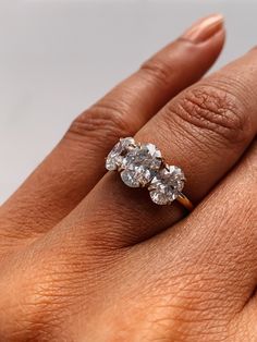 a woman's hand with a three stone diamond ring on top of her finger