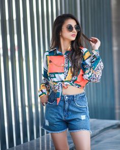 a woman wearing shorts and a colorful shirt