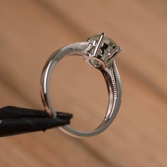 a close up of a ring with a diamond on it and a black object in the foreground