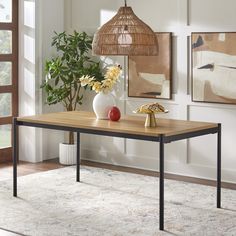 a wooden table with two vases sitting on top of it next to a plant