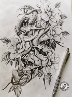 a drawing of skulls and flowers on paper with a pen in front of the image