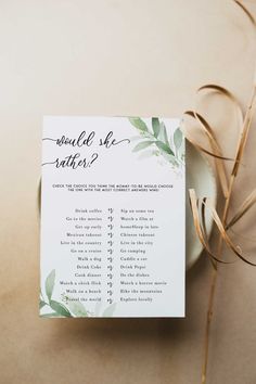 a wedding game with greenery on it next to a white plate and gold ribbon