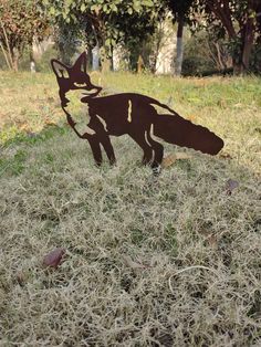 a paper cut out of a fox in the grass with trees in the back ground