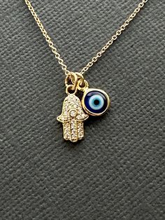 Dainty Gold Hamsa and Blue Evil eye necklace, dainty Blue Evil eye necklace, Tiny Hamsa pendant necklace, Gift for women, Christmas gift Beautifully CZ embedded gold hamsa hand pendant with Blue evil eye charm on 18K gold filled chain.  HAMSA HAND  Depicting the open right hand, an image recognized and used as a SIGN OF PROTECTION in many societies throughout history, the HAMSA is believed to provide defense against the evil eye. **CZ Hamsa Pendant measures 9mm x 16mm --------------------------- Dainty Evil Eye Charm Necklace Gift, Adjustable Blue Necklaces With Charms, Blue Dainty Charm Necklaces, Dainty Blue Charm Necklace With Adjustable Chain, Dainty Blue Necklaces With Charms, Spiritual Blue Charm Necklace, Spiritual Blue Evil Eye Charm Necklace, Adjustable Blue Charm Necklaces, Spiritual Blue Charm Necklace With Adjustable Chain