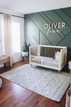 a baby's room with a white crib and green accent wall behind it