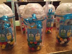 three plastic cups filled with candy and wrapped in blue ribbon