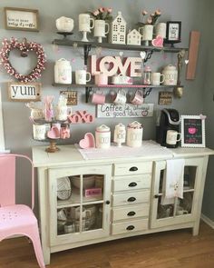 a pink chair sitting in front of a white table filled with cups and saucers