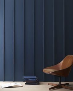 a wooden chair sitting next to a stack of books in front of a blue wall