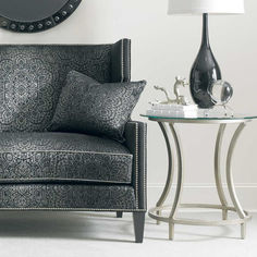 a living room with a couch, lamp and mirror on the wall above it's side table